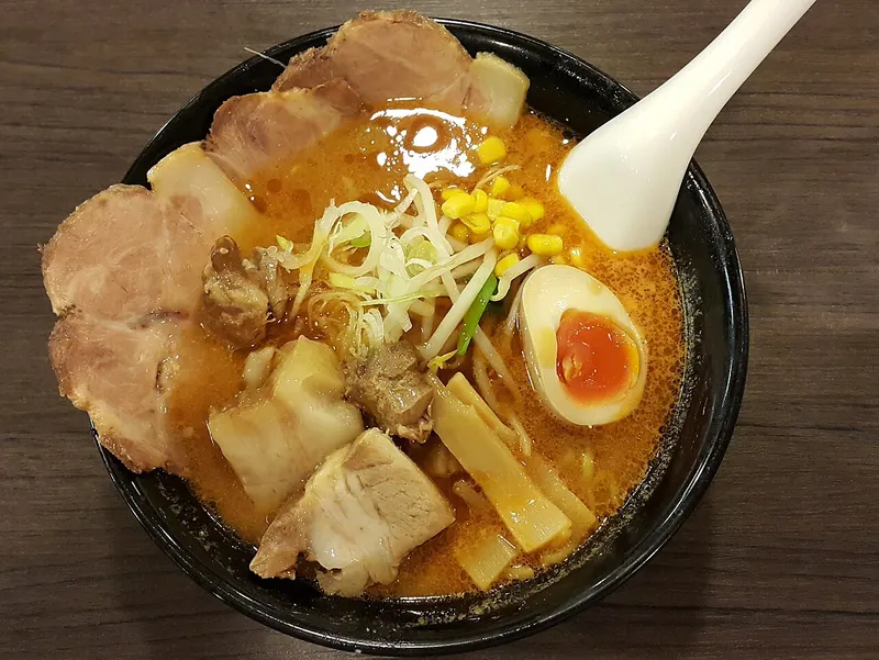 Ramen de miso con cerdo, huevo y maíz en un cuenco negro