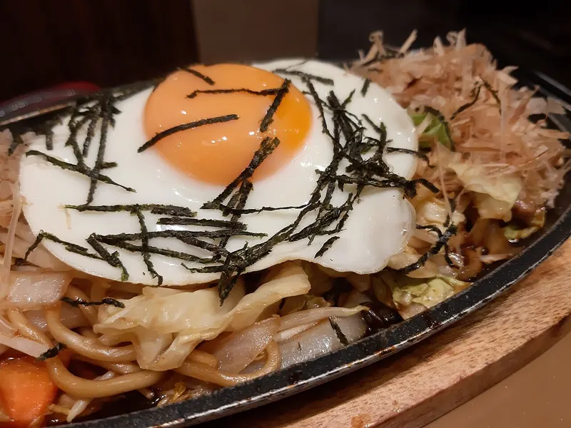Plato de yakisoba con huevo frito y alga por encima